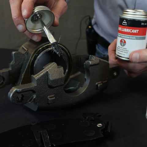 AGS SIL-Glyde 4oz brake grease being brushed onto a brake caliper; silicone lubricant for caliper hardware