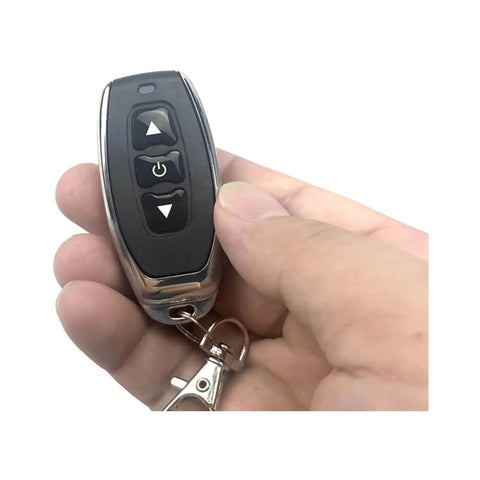 Hand holding remote of Dope Remote Control Switch Module For DC 3V To 12V Motors With Forward And Reverse Stop Mini RF Wireless Controller.