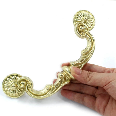 4 Pack 150 Mm Center To Center Pull Handles With Drop Down Bail Swing Zinc Alloy Rustic Vintage Style Antique Drawer Pulls For Kitchen Cabinets Gold Finish Durable Zinc Alloy Construction Includes Two Screw Types For Easy Installation, hand holding one handle