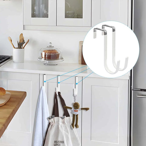 Over-cabinet door hooks in a kitchen holding towels and a bag