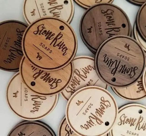 Engraved wooden tags for "Stone River Soaps" in various wood tones, featuring logo and small animal design.