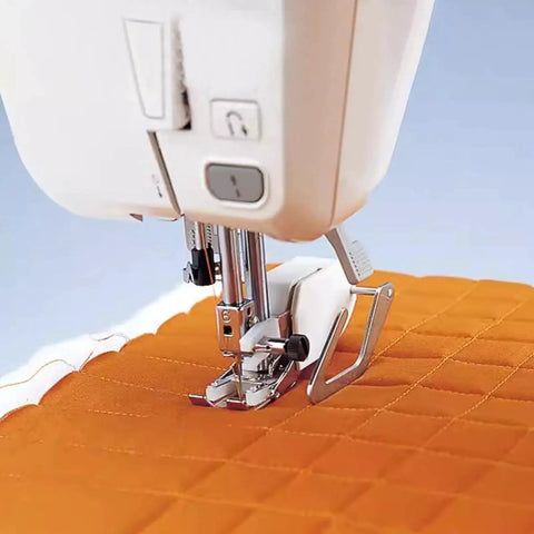 Quilting guide bar attached to sewing machine presser foot over orange quilt fabric