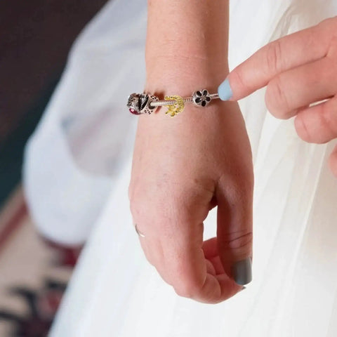 Close-up of a bracelet with Dope Vintage Style Crown Charms Set, 50 Pcs Alloy Gold Tone Crown Pendants on a hand.