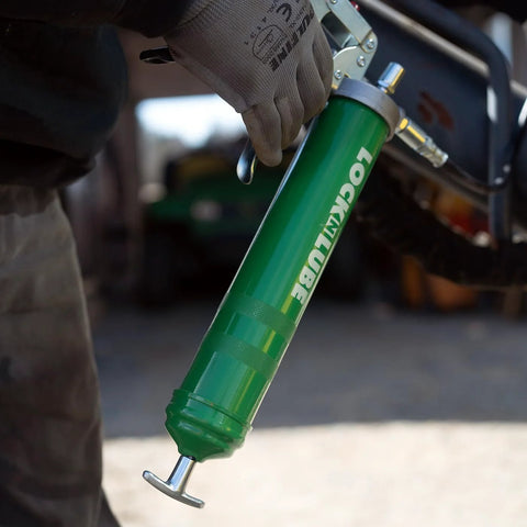 LockNLube green heavy-duty pistol-grip grease gun held by a gloved hand, with metal lever.