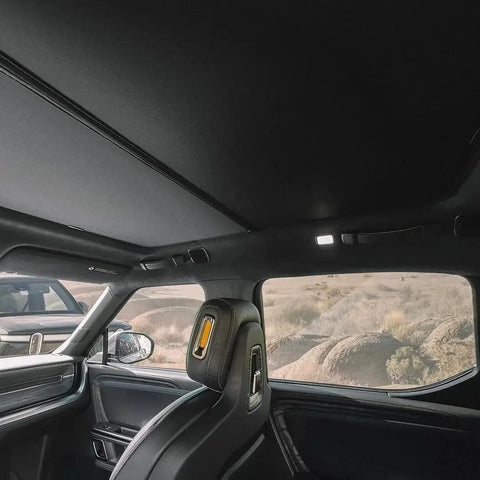 Interior view of a Rivian R1S with R1S Roof Sunshade Two Piece Full Blackout installed, blocking sunlight from roof glass.