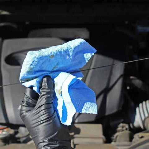 Blue V40 Value Series Center Pull Wiper Sheets being used to clean an engine dipstick, showing oil absorption and durability.
