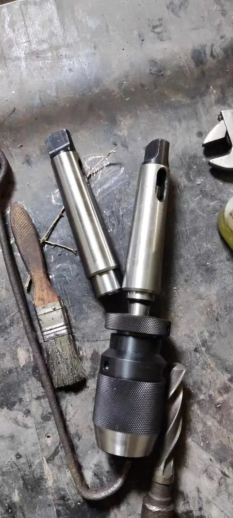 Two Morse taper adapters and drill chuck sleeve, steel with knurled black collar, front view