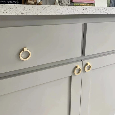 6 Pcs Brushed Brass Cabinet Ring Pulls Set In Zinc Alloy With Durable Single Hole Design installed on gray kitchen cabinets.