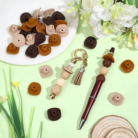 Cowboy Hat Silicone Beads Set For Jewelry Making And DIY Craft With Mini Western Cowboys 3D Charms Beadable Pens Focal Spacers Bulk Rustic Brown Beige Burnt Yellow Hues 30 Pcs on display with pen and keychain