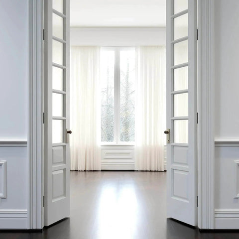 Interior view of double white doors opening towards a bright window, showcasing potential installation context for Three Pack Of 304 Stainless Steel Door Hinges In Matte Black With Non Removable Pin Heavy Duty Ball Bearing 3 Point Five Inch For Commercial And Residential Doors With One Quarter Inch Radius.