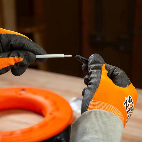 Hands holding components of Non Conductive Fish Tape Repair Kit For Fiberglass Tapes Made In USA, against orange tape