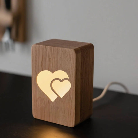 Wooden night light with illuminated double heart design for ambient room lighting.
