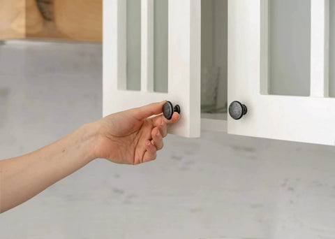 Hand opening cabinet door with Clear Self Stick Cabinet Bumper Pads Twenty Pack Round One Half Inch Rubber Cushions visible on knob