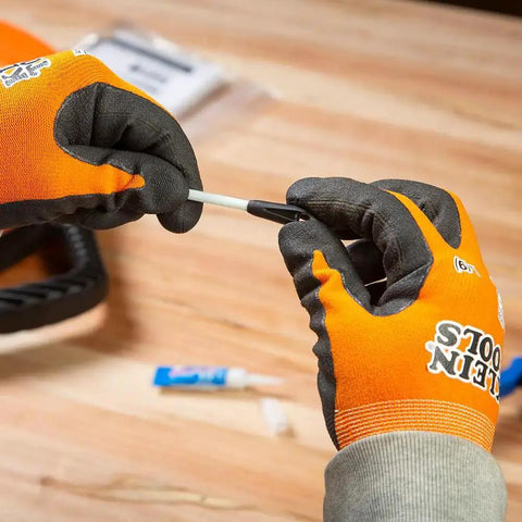 Hands using Non Conductive Fish Tape Repair Kit For Fiberglass Tapes Made In USA with glue and eyelet on table.