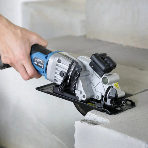 Pro Grade Mini Cordless Circular Saw With Laser Guide And Rip Guide For Precise DIY Cuts, 4-1/2 Inch Blade, 3400 RPM No-Load, Includes 24T And 60T High Quality Blades, Max Cutting Depth 1-11/16 At 90 Degrees And 1-1/8 At 45 Degrees, Blue being used on concrete block