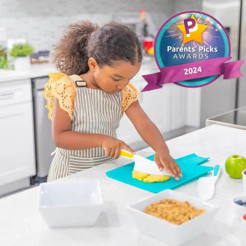 Child using a Kids Cutting Set With Safe Montessori Kitchen Knives And Cookie Cutters For Toddlers, slicing on a teal cutting board.