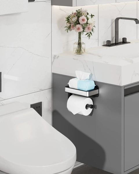 Toilet Paper Holder With Top Shelf And Phone Storage Adhesive And Screw Wall Mount Matte Black Bathroom Organizer For Washroom And RV Space Saving 7 Point 1 Inch Wide installed next to a sink with flowers.