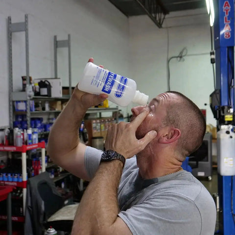 Man using Eye Wash Solution 32 Oz Sterile Isotonic Buffered Eye Rinse for flushing and irrigating eyes in workshop setting