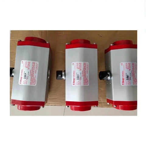 Three silver pneumatic valve actuators with red end caps on cardboard