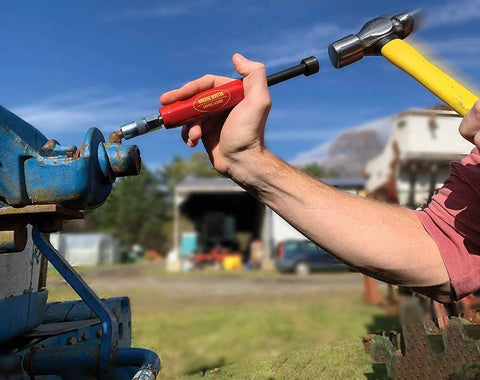 Grease Buster tool with red handle and LockNLube branding used to flush grease from blue hydraulic fittings.