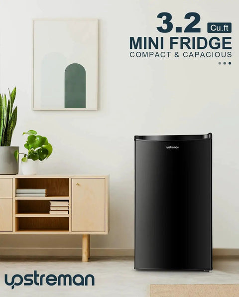 Black 3.2 Cu Ft Single Door Mini Fridge With Freezer For Dorm Office Bedroom next to wooden cabinet and plant
