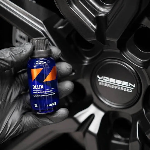 DLUX Wheel and Trim Ceramic Coating 30mL with UV protection held in front of alloy wheel