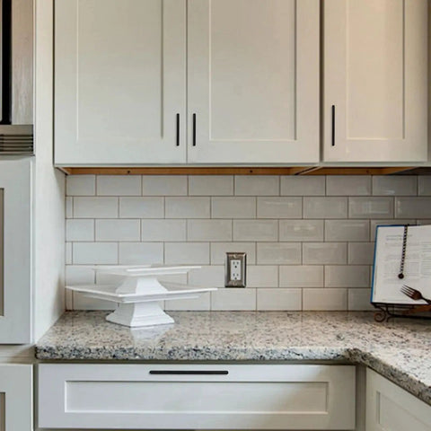 Matte black zinc alloy cabinet pulls installed on white kitchen cabinets showing 5 inch solid hardware in modern style.