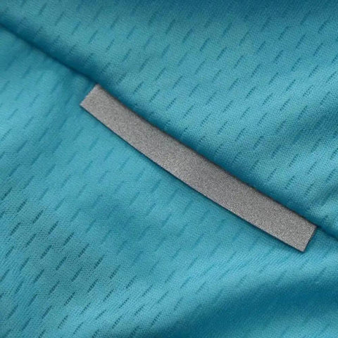 Close-up of teal fabric with diagonal textured pattern and silver reflective strip