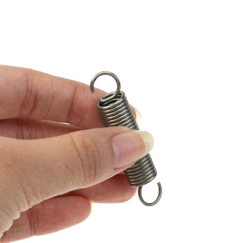 Mcredy extension spring, stainless steel with dual hook ends, held between fingers.