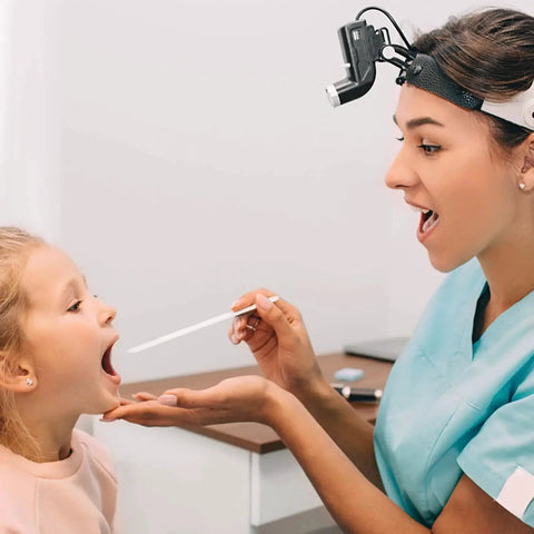 Doctor examining child's throat with medical tool in clinic
