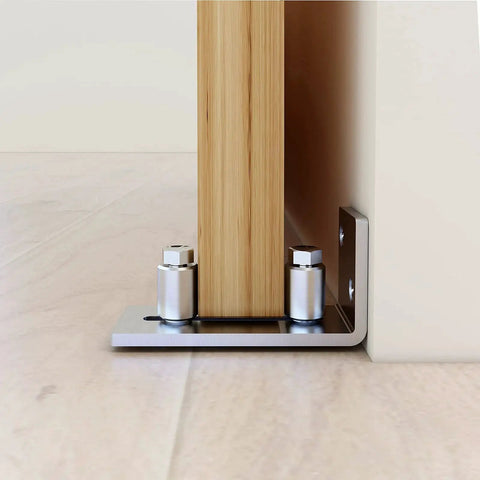 Scratch Resistant Stainless Steel Flush Mount Stay Roller Floor Guide For Doors Up To Two And One Eighth Inches Thick With Flat Bottom Design Keeps Floors Free Of Grooves And Provides Easy Wall Mount Installation With Included Screws And Hardware installed on wooden door.