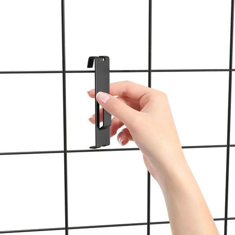 Hand placing black utility hanger on grid wall panel, part of 15 Pack Gridwall Notch Hooks Black Utility Hangers for Grid Wall Panels Pegboard Display