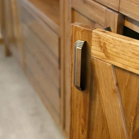 Side view of Six Pack 5 Inch Antique Brass Cup Pulls With Distinctive Layered Ribbed Multi Sectioned Design on a wooden cabinet