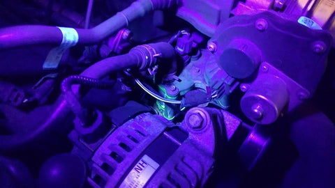 Air Conditioner UV Dye Leak Detector Kit With 68 LED UV Flashlight highlighting AC system leaks in engine bay, UV light on hoses.
