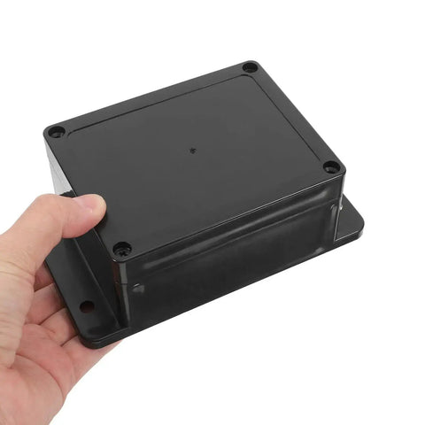 Hand holding durable waterproof outdoor electrical box plastic enclosure with fixed ear 115x90x55mm black for indoor and outdoor use.