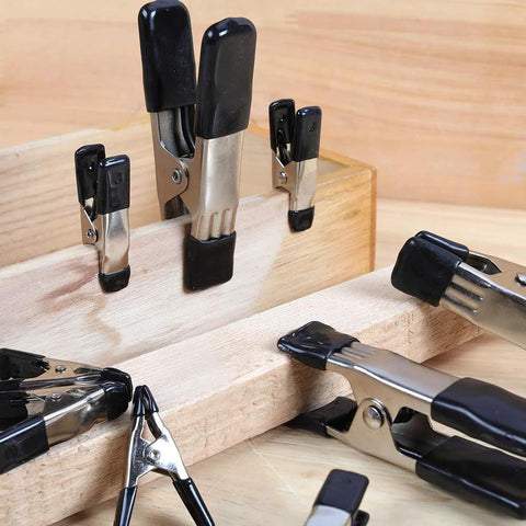 Amazon Basics 20-piece steel spring clamps set with PVC-coated tips; black and silver clamps, 3/4-inch and 1-inch sizes, on wood.