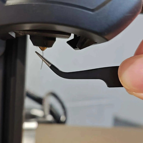 Using tweezers from the Complete 42Pcs 3D Printer Nozzle Cleaning Tool Kit for extruder maintenance on a 3D printer.