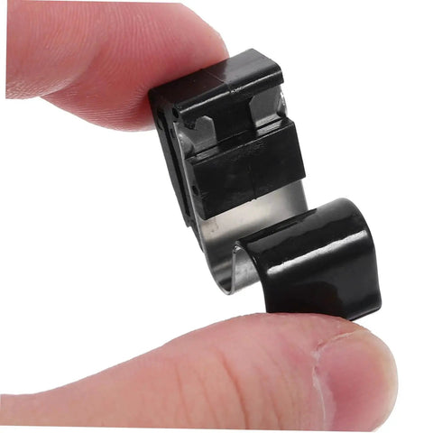 Gas tank door spring clip, black plastic housing with metal band, shown in close-up between fingers.