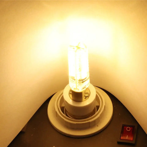 Illuminated light bulb in socket with warm glow against a white background