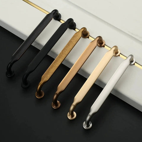 Set of metal cabinet handles in various finishes, including oil rubbed bronze, displayed on a black and white surface.
