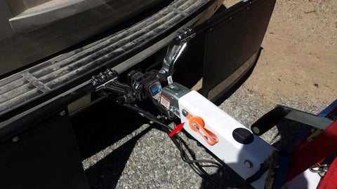 Front view of boat trailer surge brake lockout actuator attached to a white hitch with orange lockout key visible