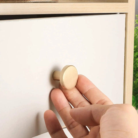Hand installing Brushed Brass Cabinet Knobs Set Of 8 With Screws And Screwdriver 20X25 Mm Solid Brass Hardware on white drawer