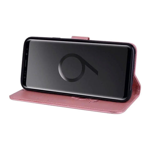 Smartphone in pink leather flip cover, standing horizontally, showing front view with screen facing forward.