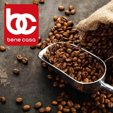 Silver scoop with coffee beans on a dark surface near a burlap sack, with a red 'bene casa' logo in the corner.