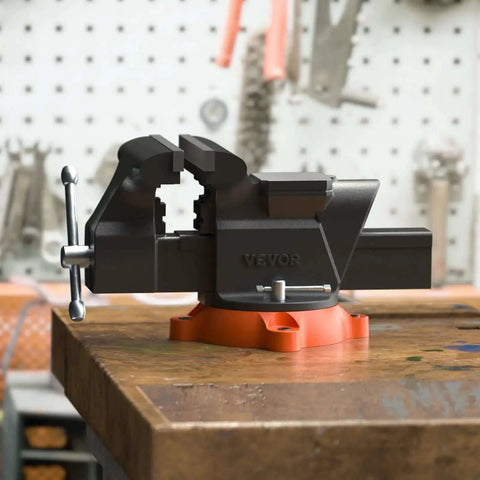 Versatile 6 Inch Bench Vise With 360 Degree Swivel And Anvil VEVOR Heavy Duty Ductile Iron Workbench Vise on a wooden table in workshop.
