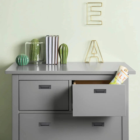 Gray dresser with open drawer, books, and decorative items