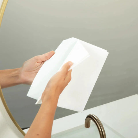 Hands holding Miracle Cleaning Cloths 4 Pack Just Water Streak Free Reusable 16x16 near a bathroom mirror.