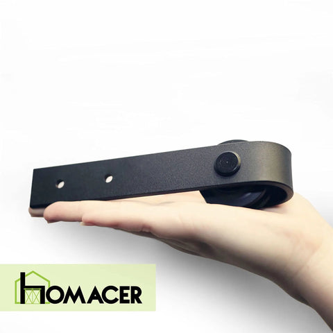Close-up of a hand holding a component from the Mini Black Rustic Sliding Barn Door Hardware Kit For Two Doors 54 Inch Flat Track Non Bypass With Classic Roller Design Ideal For TV Stand Cabinet Vanity And Console Use.