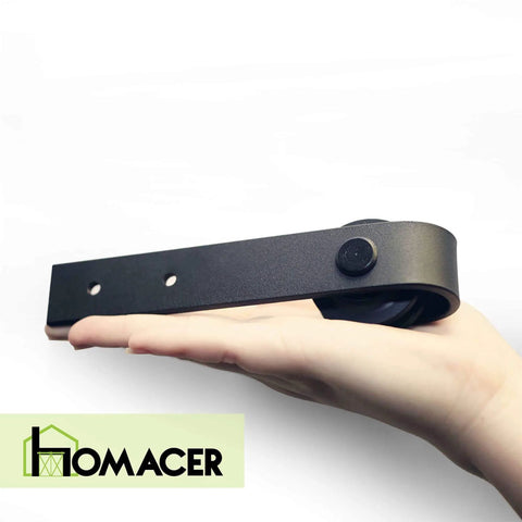 Hand holding a component of the Mini Black Rustic Non-Bypass Sliding Barn Door Hardware Kit for Single Door with Classic Roller Design.