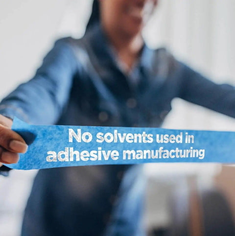 Person holding PROSharp Painter's Tape showing 'No solvents used in adhesive manufacturing' text, focus on tape details.